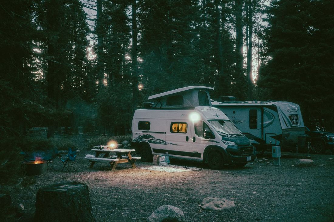 Campervan and caravan at a forest campsite at dusk